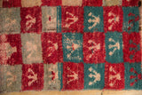 Detail of a Tulu rug's worn texture, with red and turquoise checkered panels showing foundation.