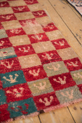 The shaggy pile and checkered trefoil motifs of a distressed Tulu rug seen down its length.