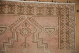 Corner view of a distressed Oushak showing the dusty rose prayer mehrab and geometric border.