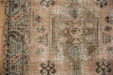 Distressed Hamadan rug detail: textured pile, serrated border pattern, and geometric motifs in beige, teal, brown.