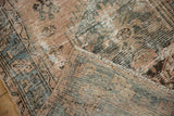 Worn texture and faded beige, teal, and brown colors of a distressed Hamadan rug.