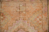 Distressed pile texture of a vintage Kurd runner with tangerine, ivory, and magenta hues.
