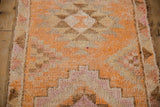 Distressed short pile detail of vintage Kurd runner, geometric tangerine, ivory, and magenta pattern.