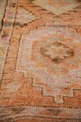 Distressed short pile on the vintage Kurd rug, showing geometric medallions in tangerine orange.
