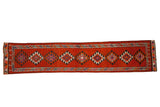 Vintage Kurd runner rug with repeating rust and aubergine geometric diamond medallions.