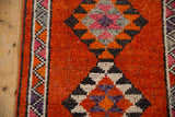 Kurd rug's serrated diamond medallion in rust, tangerine, charcoal, and aubergine.