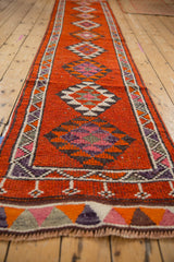 Kurd runner end detail, showing secured fringe, geometric tangerine, aubergine, and blush border.