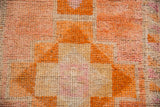 Distressed Kurd rug pile, showing worn geometric patterns in tangerine, rust, and pale pink.
