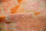 Thick, distressed pile of the Kurd rug with raspberry, tangerine, and rust colors.
