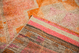 Distressed cantaloupe and raspberry pile, showing knot heads and striped hand-knotted reverse.