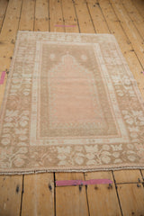 A distressed vintage Oushak prayer rug in soft, time-worn shades of dusty rose and beige.