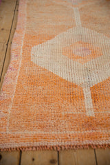 Close-up of vintage distressed Kurd rug with pale tangerine orange pile and geometric diamond.