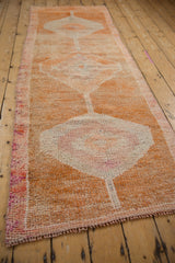 Textured detail of distressed vintage Kurd runner, with faded orange and magenta pile, intact selvage.