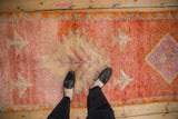 Distressed vintage Kurd runner's textured pile reveals vibrant orange and raspberry motifs.