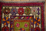 Vintage Oushak rug corner with moss green, deep violet, orange, and cherry red motifs.