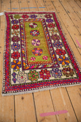Vintage Oushak rug's side selvage, wide red border, moss green field, and worn floral motifs.