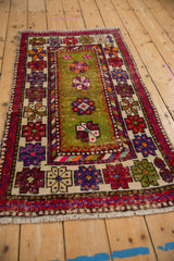 Vintage Oushak rug's banded border with red, purple floral motifs; moss green field shows pile wear.