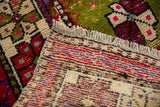 Vintage Oushak rug's woven fringe and foundation, revealing moss green, red, and beige patterns.