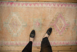 Distressed vintage Kurd runner pile showing cantaloupe, ivory, and faded magenta geometric patterns.