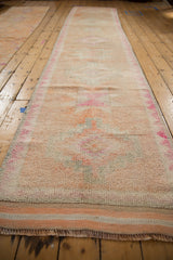 Distressed vintage Kurd runner with short pile, faded magenta, cantaloupe, ivory geometric medallions.