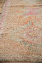 Textured pile of a distressed Kurd runner rug in cantaloupe, faded magenta, and ivory.