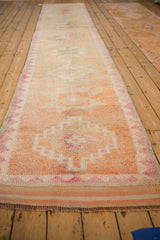Distressed Kurd runner, showing textured pile and geometric motifs in cantaloupe, ivory, magenta.