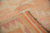 Short, textured pile and woven side of distressed Kurd runner in cantaloupe, ivory, magenta.