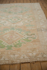 Distressed Kars carpet pile, showing green geometric patterns and abrashed beige field.
