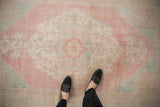 Overhead view of a vintage Oushak rug's distressed pile and faded red and blue medallion.
