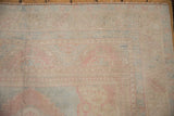 Close view of the evenly worn pile on a distressed Oushak carpet in pale red, blue, and sand tones.