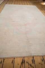 Angled view highlighting the even wear and low pile texture of a vintage distressed Oushak rug.
