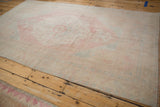 Long perspective of a distressed Oushak carpet highlighting its evenly worn texture and soft colors.