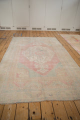 Angled view of a distressed Oushak carpet, showing the even wear and soft, faded palette.