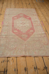 Distressed Oushak rug corner detail, dusty raspberry, ivory tones, and visible fringe.