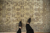 Distressed vintage Oushak rug with soft cream field, faded rose floral motifs, and stylized border.