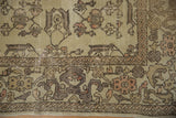 Decorative corner of a distressed vintage Oushak rug, featuring muted rose florals and cloud-band border.