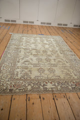 Detailed view of distressed Oushak rug's cream field with rose and silver plant motifs.