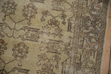 Distressed vintage Oushak rug showing time-softened cloud-band border and floral motifs.