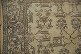 Distressed Oushak rug close-up: creamy field, rose florals, and geometric cloud-band border details.