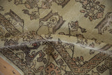 Folded distressed Oushak rug with muted dusty cream, rose, and vine botanical patterns.