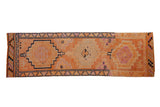 Vintage distressed Kurd rug runner with tangerine orange, magenta, and navy geometric medallions.
