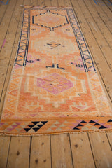 Distressed geometric patterns in tangerine orange, magenta, and navy on a vintage Kurd runner.