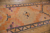 Vintage distressed Kurd runner showing tangerine, magenta, navy geometric patterns and aged texture.
