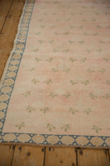 Faded pink field with stylized pale moss green clovers and dusty denim blue floral border.