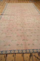 Distressed Sparta carpet: faded pink field, green clover leaves, and denim blue floral border.