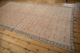 Distressed vintage Sparta carpet: pink field with clover, dusty blue and ivory border.