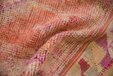 Distressed textured pile of vintage Kurd runner with orange, ivory, and magenta geometric pattern.