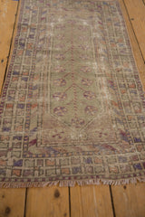 Distressed Oushak runner's central tree of life motif with pinwheel blossoms and faded texture.