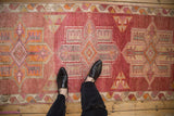 Distressed vintage Kurd runner showing geometric medallions in dusty cochineal and tangerine tones.