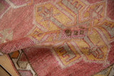 Close-up of distressed Kurd runner pile, revealing geometric motifs in faded pink, yellow, and beige.